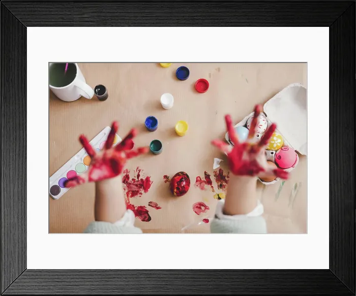 Framed Print : From above crop palms of kid in paints near Easter eggs in container and set of bright colors on carton background Framed Print : From above crop palms of kid in paints near Easter eggs in container and set of bright colors on carton background