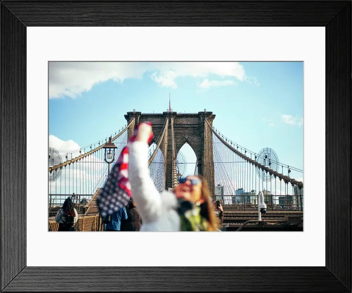 Framed Print : Woman standing on Brooklyn Bridge holding the American flag, New York, United States