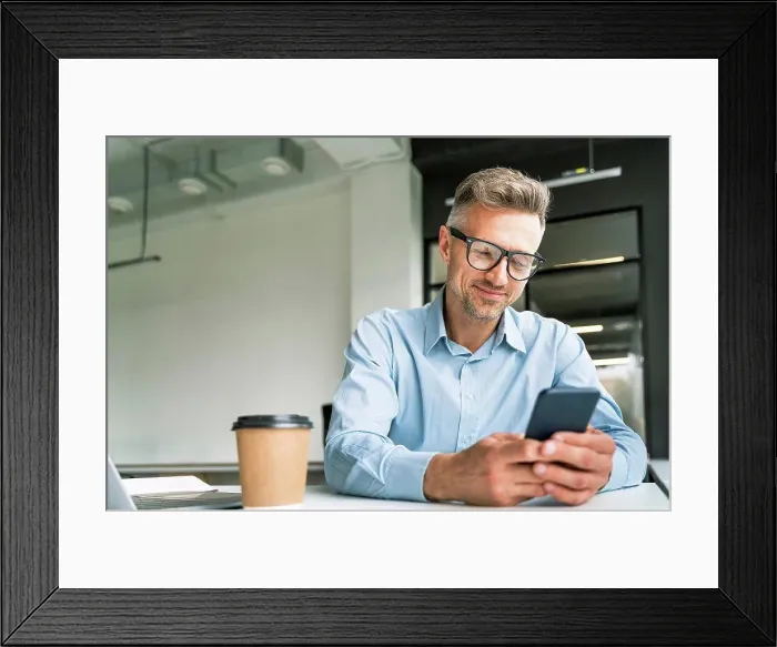 Framed Print : Male business professional using smart phone in office Framed Print : Male business professional using smart phone in office