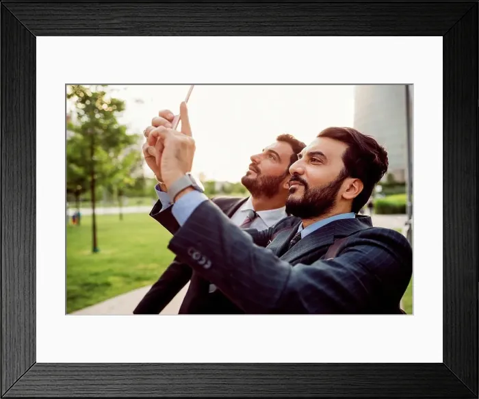 Framed Print : Two businessmen wearing suits standing outdoors, checking their mobile phones Framed Print : Two businessmen wearing suits standing outdoors, checking their mobile phones