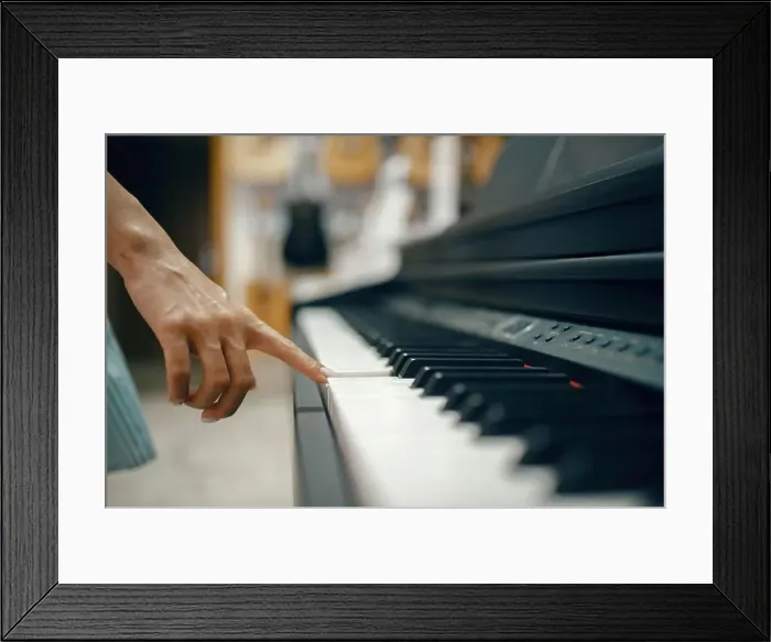 Framed Print : Young woman choosing digital piano in music store