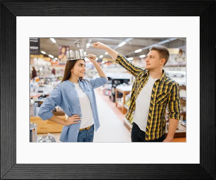 Framed Print : Young couple jokes with ladle and pan in houseware store Framed Print : Young couple jokes with ladle and pan in houseware store