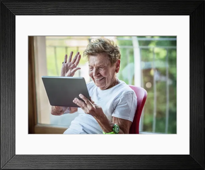 Framed Print : A very senior woman using digital tablet on apartment balcony Framed Print : A very senior woman using digital tablet on apartment balcony