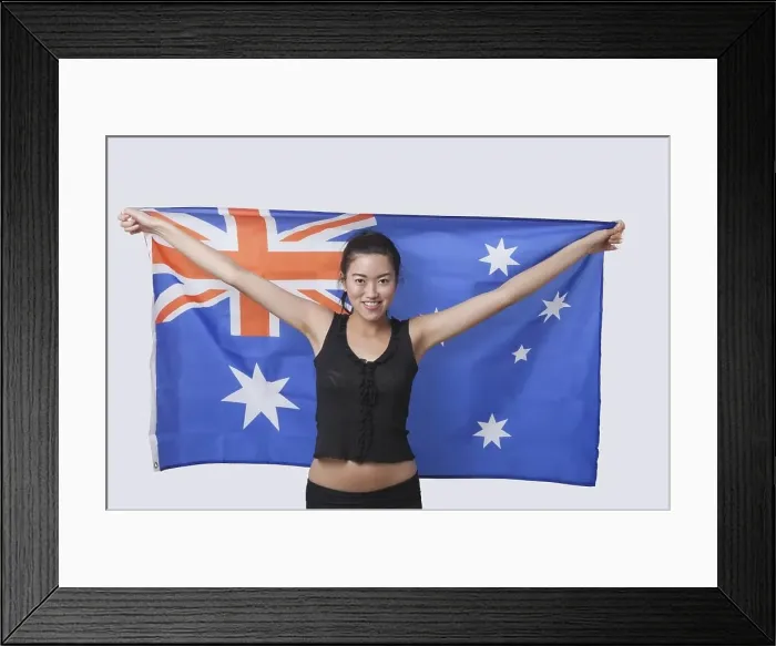 Framed Print : Portrait of smiling young woman holding Australian flag over white background