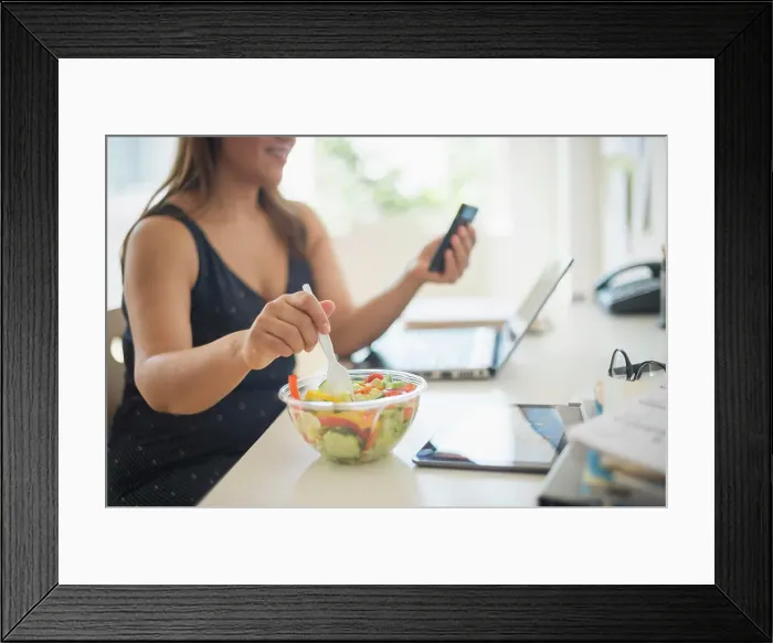 Framed Print : Woman working in home office and eating salad Framed Print : Woman working in home office and eating salad