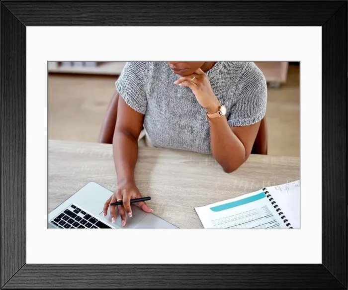 Framed Print : Getting the job done. a businesswoman working on her laptop