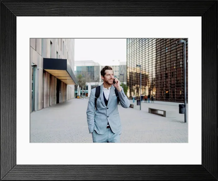 Framed Print : Businessman standing with hand in pocket talking on smart phone