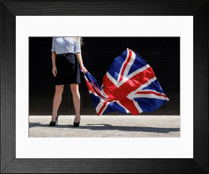 Framed Print : Businesswoman standing outdoors holding British Flag Framed Print : Businesswoman standing outdoors holding British Flag