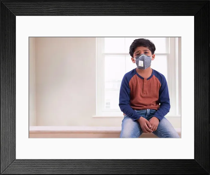 Framed Print : Young boy looking tired of wearing a pollution mask at home. (Children)