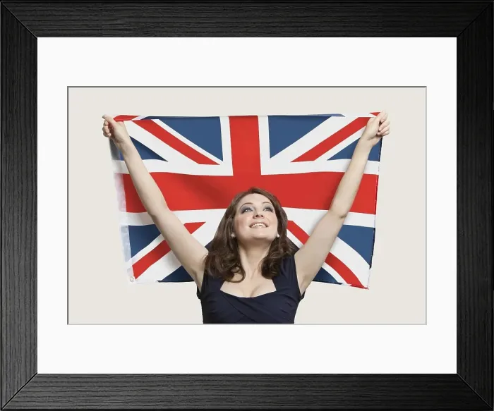 Framed Print : Young woman holding British Flag with pride over gray background Framed Print : Young woman holding British Flag with pride over gray background