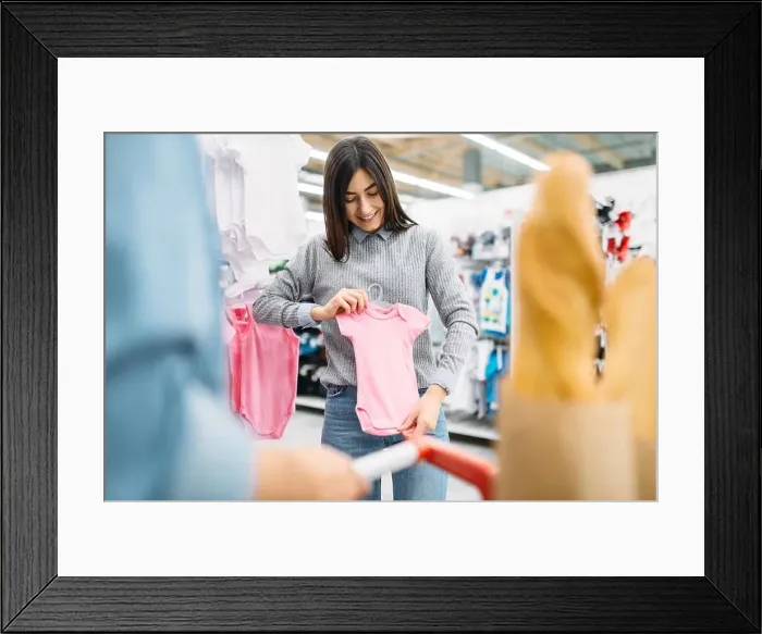 Framed Print : Young mother buying childrens clothes in store Framed Print : Young mother buying childrens clothes in store