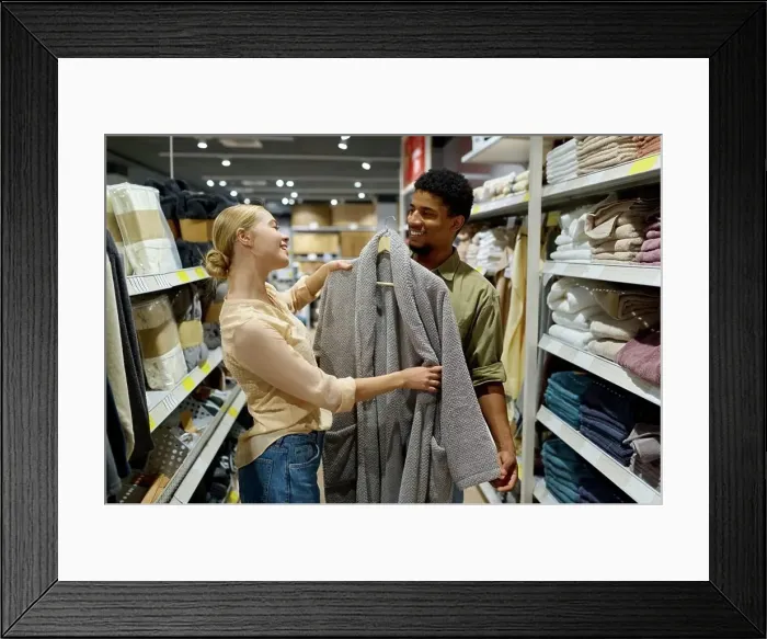Framed Print : Interracial family couple customer choosing bathrobe in shop