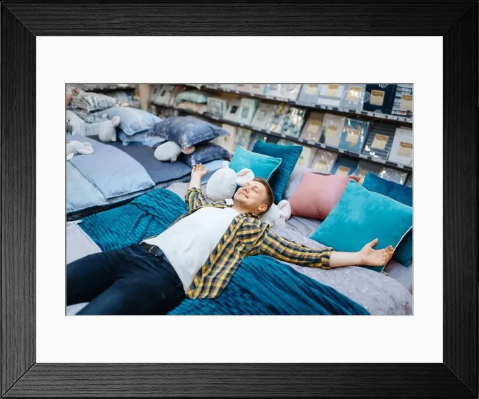 Framed Print : Young man lying on the bed in bedding store Framed Print : Young man lying on the bed in bedding store
