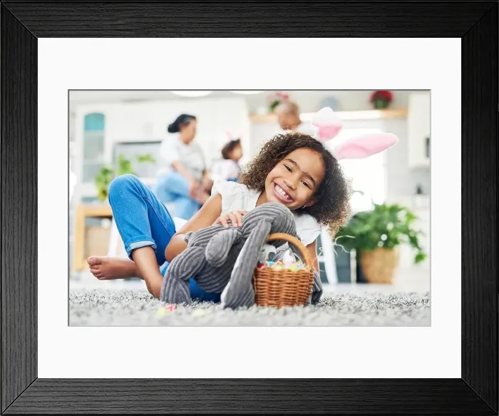 Framed Print : a young girl sitting on the floor with easter eggs at home
