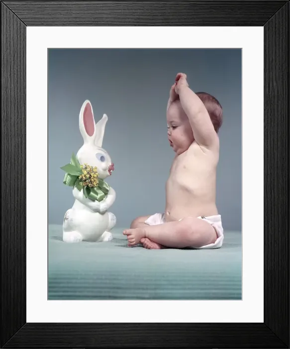 Framed Print : 1950s BABY FULL FIGURE SEATED ARMS ABOVE HEAD LOOKING AT EASTER RABBIT TOY GREEN BOW FLOWERS Framed Print : 1950s BABY FULL FIGURE SEATED ARMS ABOVE HEAD LOOKING AT EASTER RABBIT TOY GREEN BOW FLOWERS