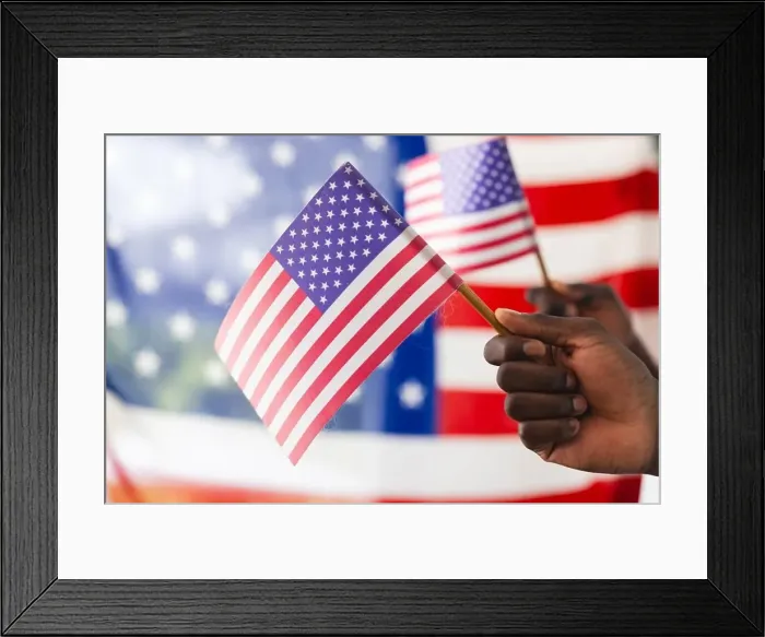 Framed Print : African American hand holding an American flag with another flag in the background