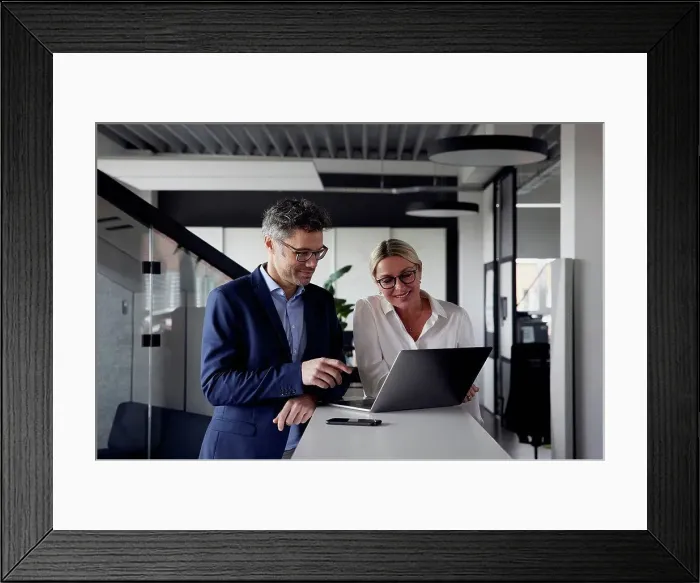 Framed Print : Business colleagues sharing laptop at office