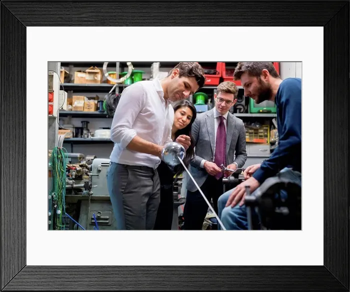 Framed Print : Colleagues in discussion in fencing prop workshop