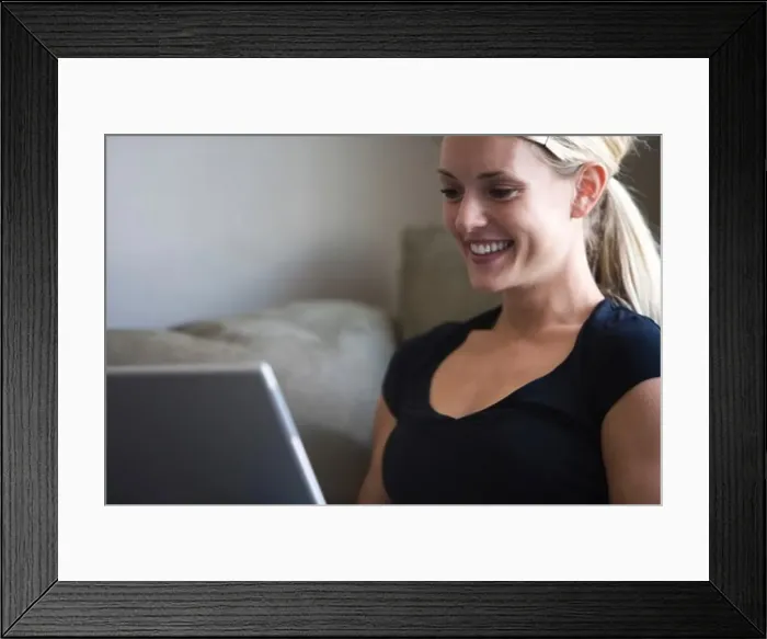 Framed Print : Woman on a laptop looking at a business card