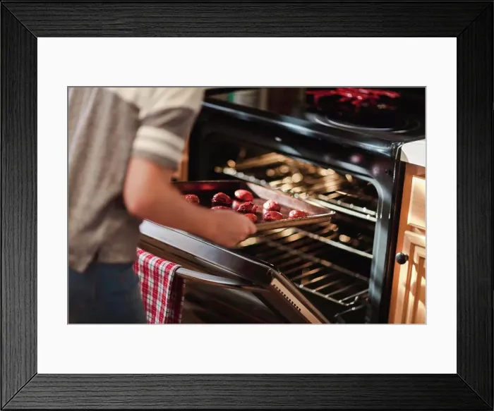 Framed Print : Girl placing tray of christmas cookies into oven, mid section Framed Print : Girl placing tray of christmas cookies into oven, mid section