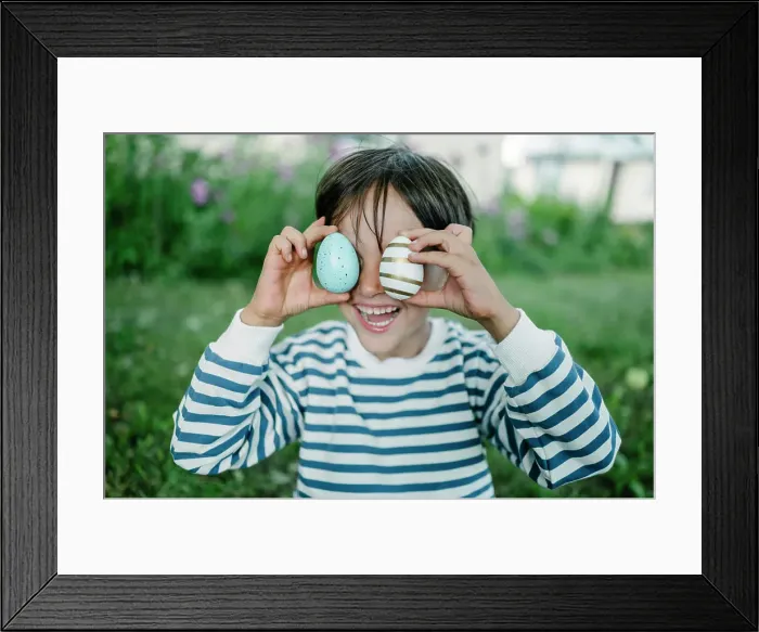 Framed Print : Boy covering eyes with easter eggs in park