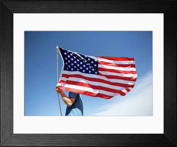 Framed Print : Man holding American flag under blue sky Framed Print : Man holding American flag under blue sky