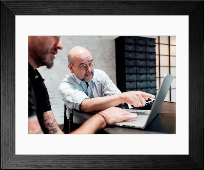 Framed Print : Colleagues looking at laptop together Framed Print : Colleagues looking at laptop together