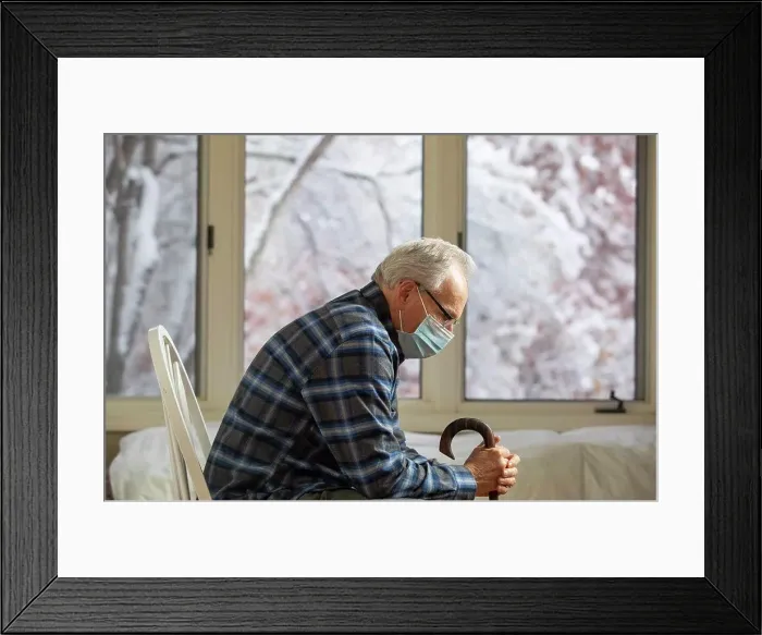 Framed Print : Senior man wearing protective mask sitting near window
