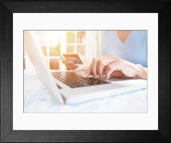 Framed Print : Cropped view of woman holding credit card using laptop