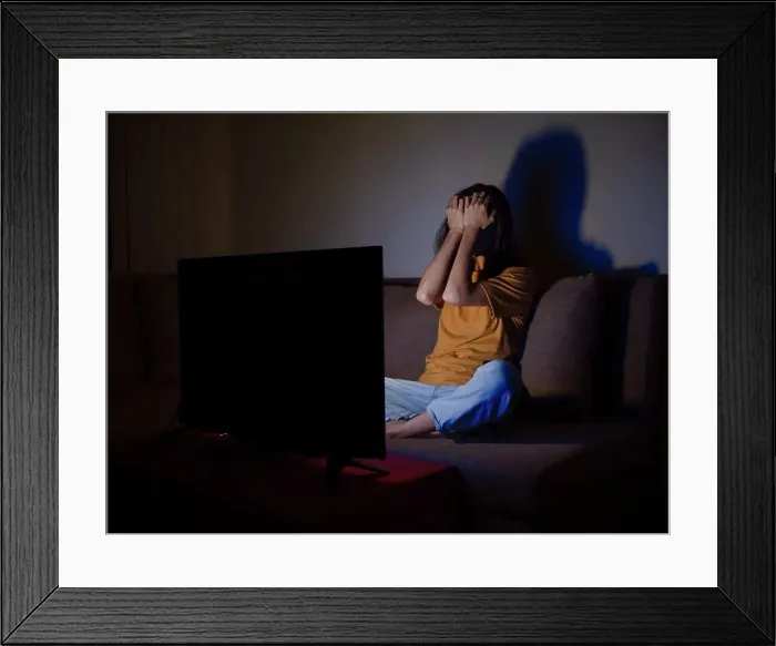 Framed Print : Young woman covering face with palms watching tv at night time Framed Print : Young woman covering face with palms watching tv at night time