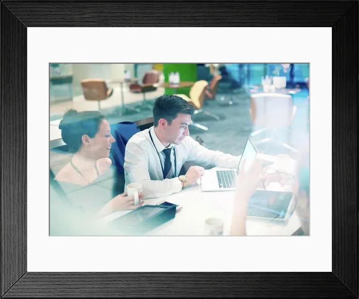 Framed Print : Businessman and woman sitting in airport lounge, using laptop Framed Print : Businessman and woman sitting in airport lounge, using laptop