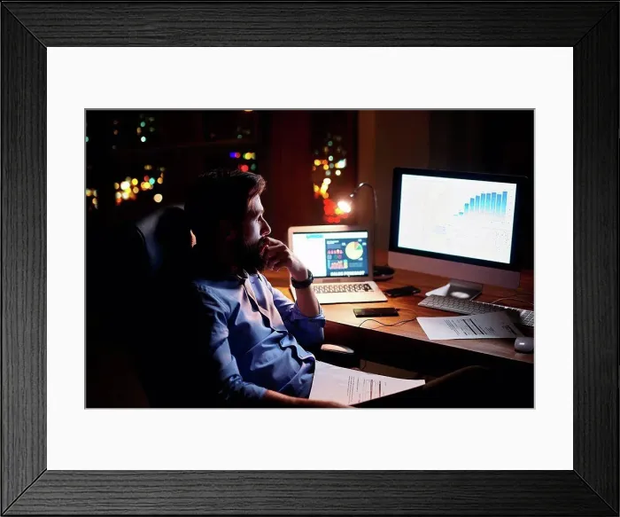 Framed Print : Young businessman staring at computer on office desk at night Framed Print : Young businessman staring at computer on office desk at night