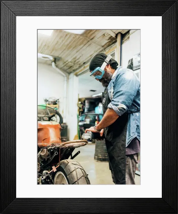 Framed Print : Mature man, working on motorcycle in garage Framed Print : Mature man, working on motorcycle in garage