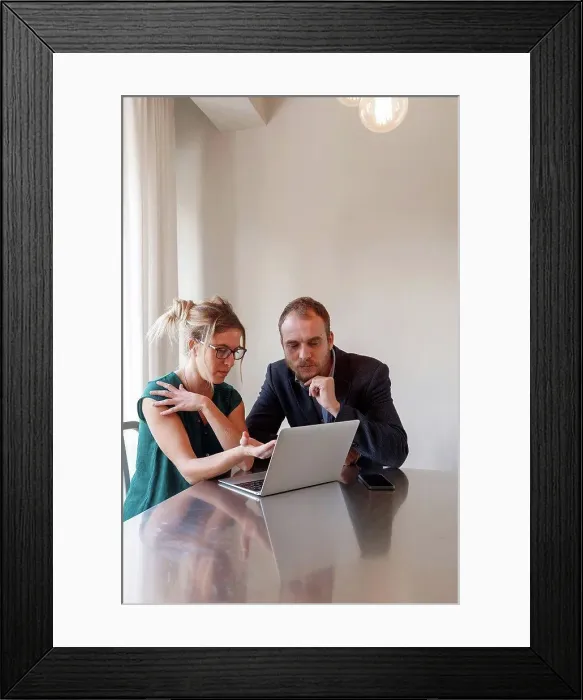 Framed Print : Mid adult couple sitting at table, looking at laptop Framed Print : Mid adult couple sitting at table, looking at laptop