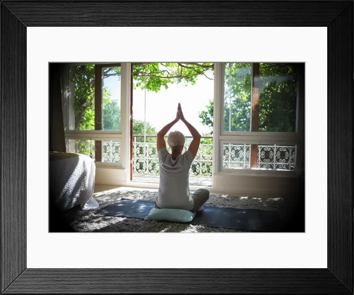 Framed Print : Serene senior woman practicing yoga at sunny tranquil balcony doorway Framed Print : Serene senior woman practicing yoga at sunny tranquil balcony doorway
