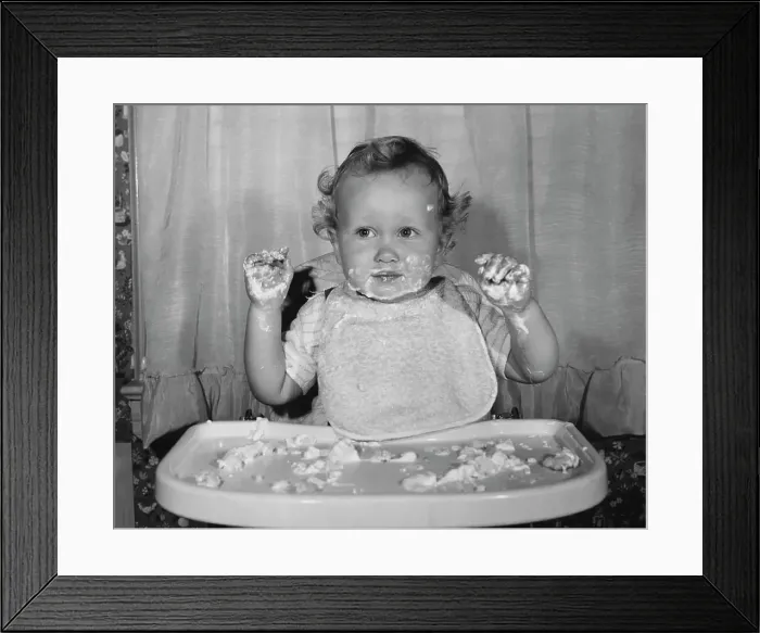Framed Print : Close-up of a baby sitting in a high chair with food on his face and hands