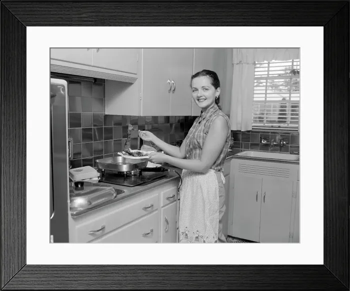 Framed Print : Woman holding plate with food in the kitchen and looking at camera Framed Print : Woman holding plate with food in the kitchen and looking at camera