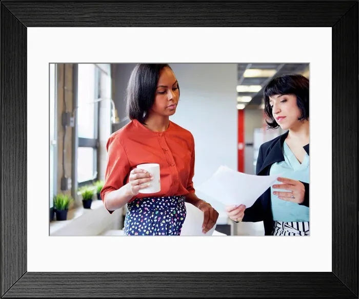 Framed Print : Two businesswomen in office, looking at document