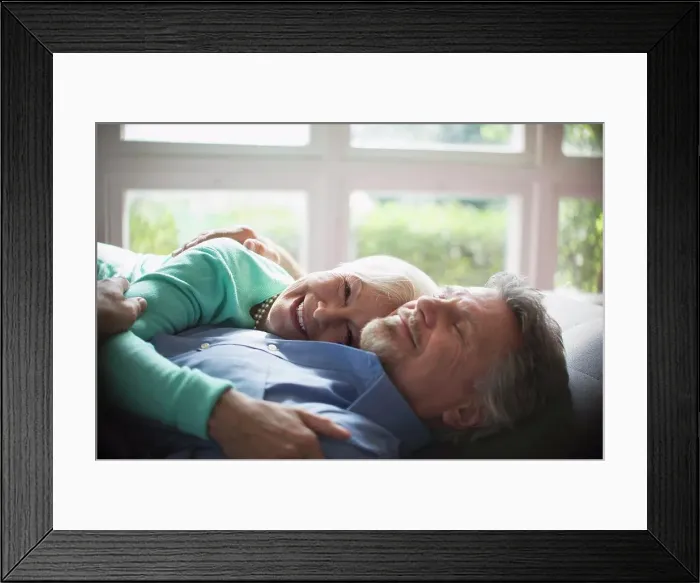 Framed Print : Happy senior couple cuddling by sunny window