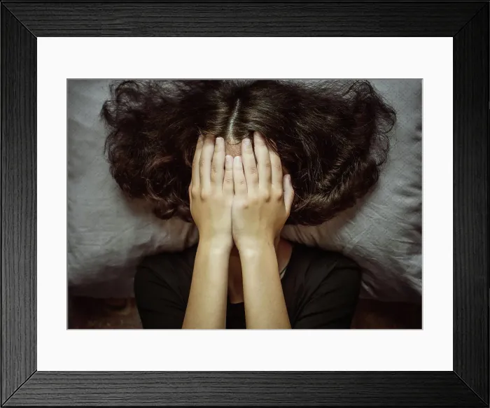 Framed Print : Girl closing face with palms, lying on pillow Framed Print : Girl closing face with palms, lying on pillow