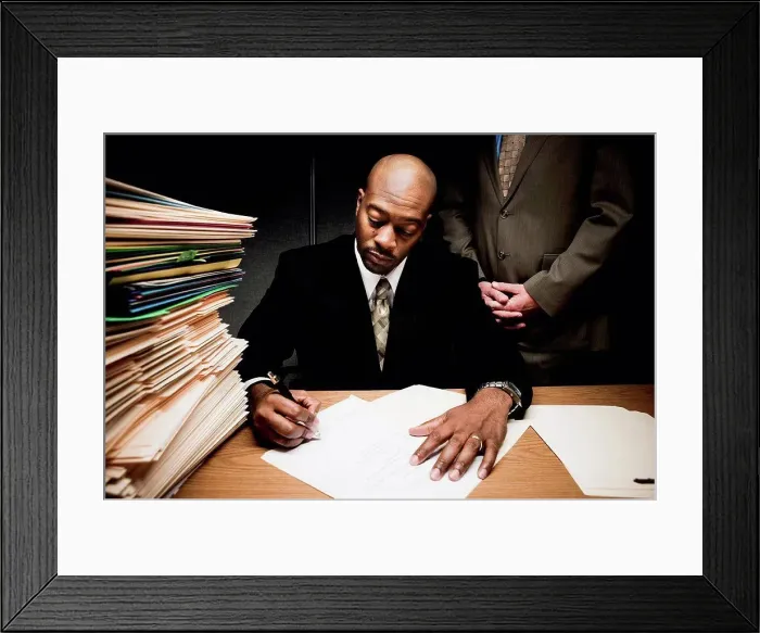 Framed Print : Man doing paperwork with man behind him Framed Print : Man doing paperwork with man behind him