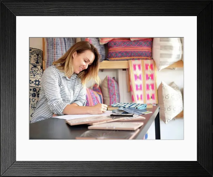 Framed Print : Female interior designer drawing designs at desk in retail studio Framed Print : Female interior designer drawing designs at desk in retail studio