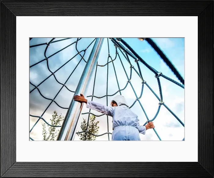 Framed Print : Rear view of boy in astronaut costume climbing up playground climbing frame Framed Print : Rear view of boy in astronaut costume climbing up playground climbing frame