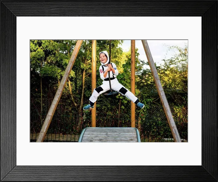 Framed Print : Portrait of boy in astronaut costume riding on playground zip wire