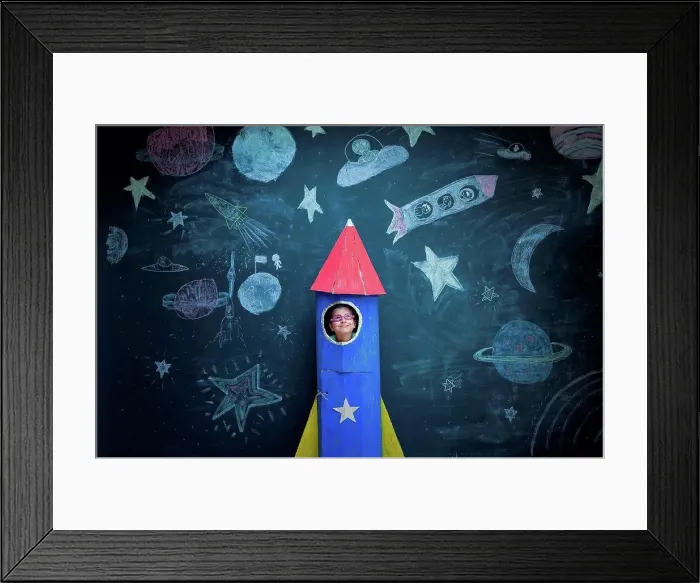 Framed Print : Portrait of girl in handmade space rocket in front of space themed chalk drawings