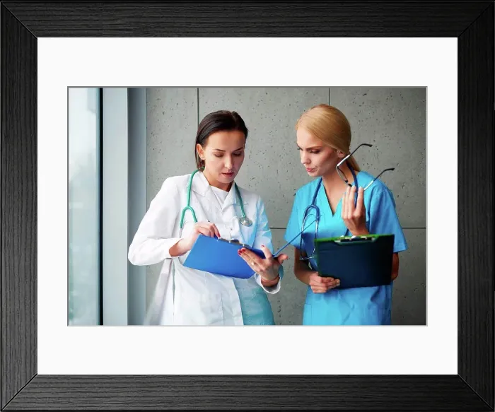 Framed Print : Doctor and surgeon talking in hallway, looking at clipboard