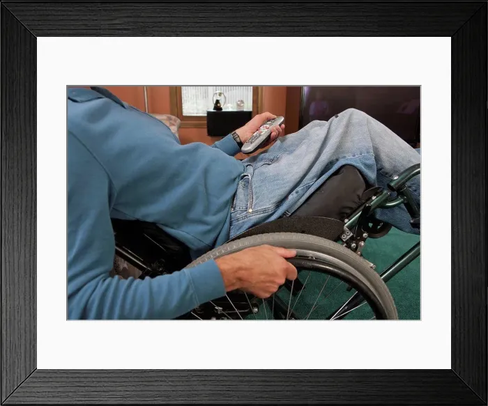 Framed Print : Man with spinal cord injury in a wheelchair using a remote control