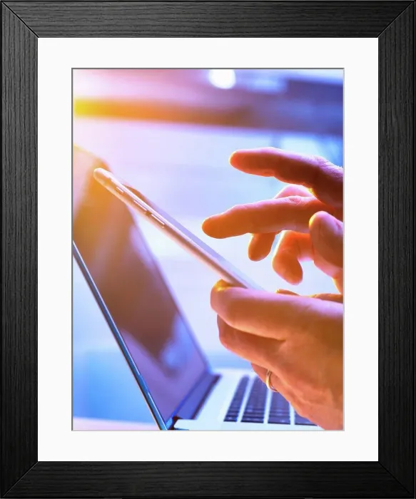 Framed Print : Man using a mobile phone with a laptop in the background Framed Print : Man using a mobile phone with a laptop in the background