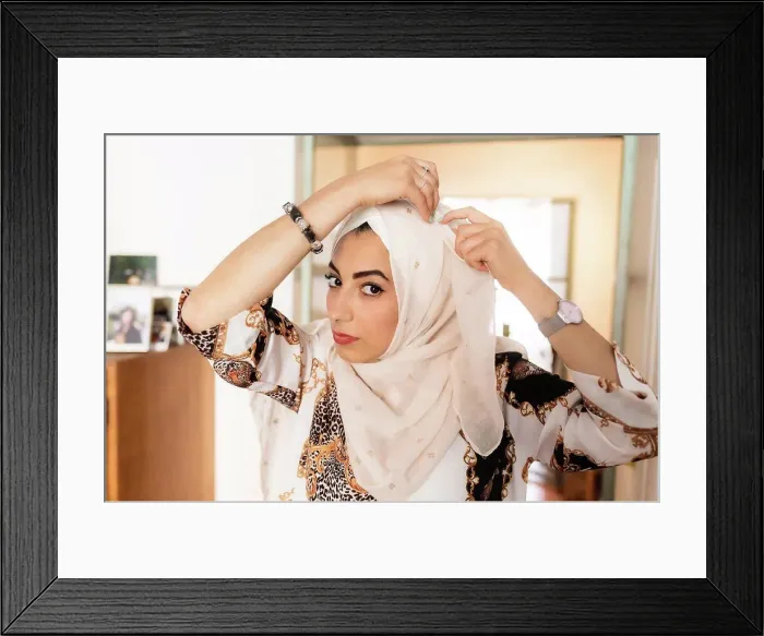 Framed Print : Young muslim woman putting on hijab headscarf