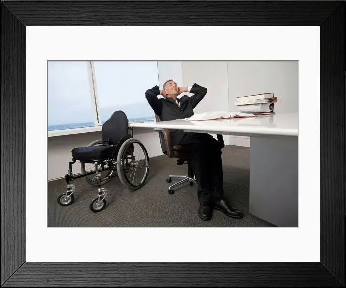 Framed Print : Businessman with a wheelchair relaxing in office Framed Print : Businessman with a wheelchair relaxing in office